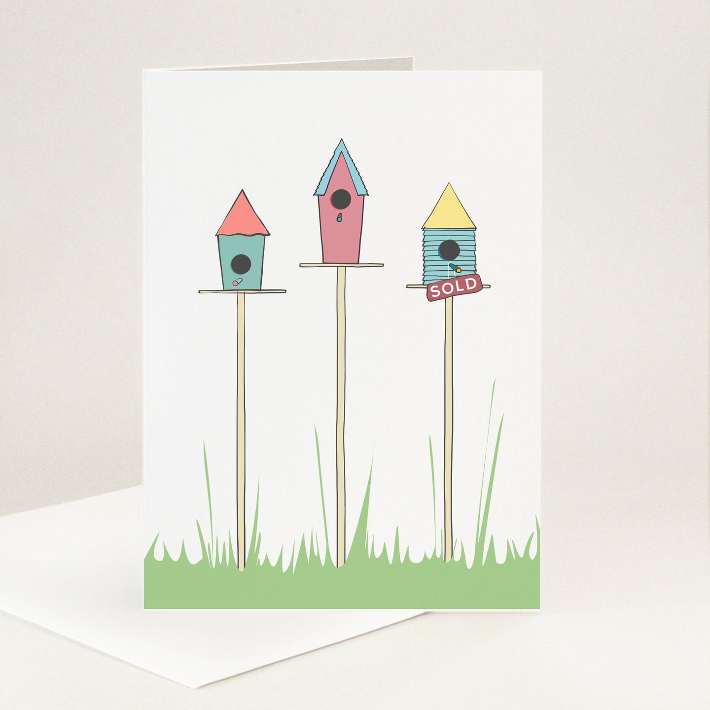 Three colourful birdhouses on poles with one having a sold sign on it.