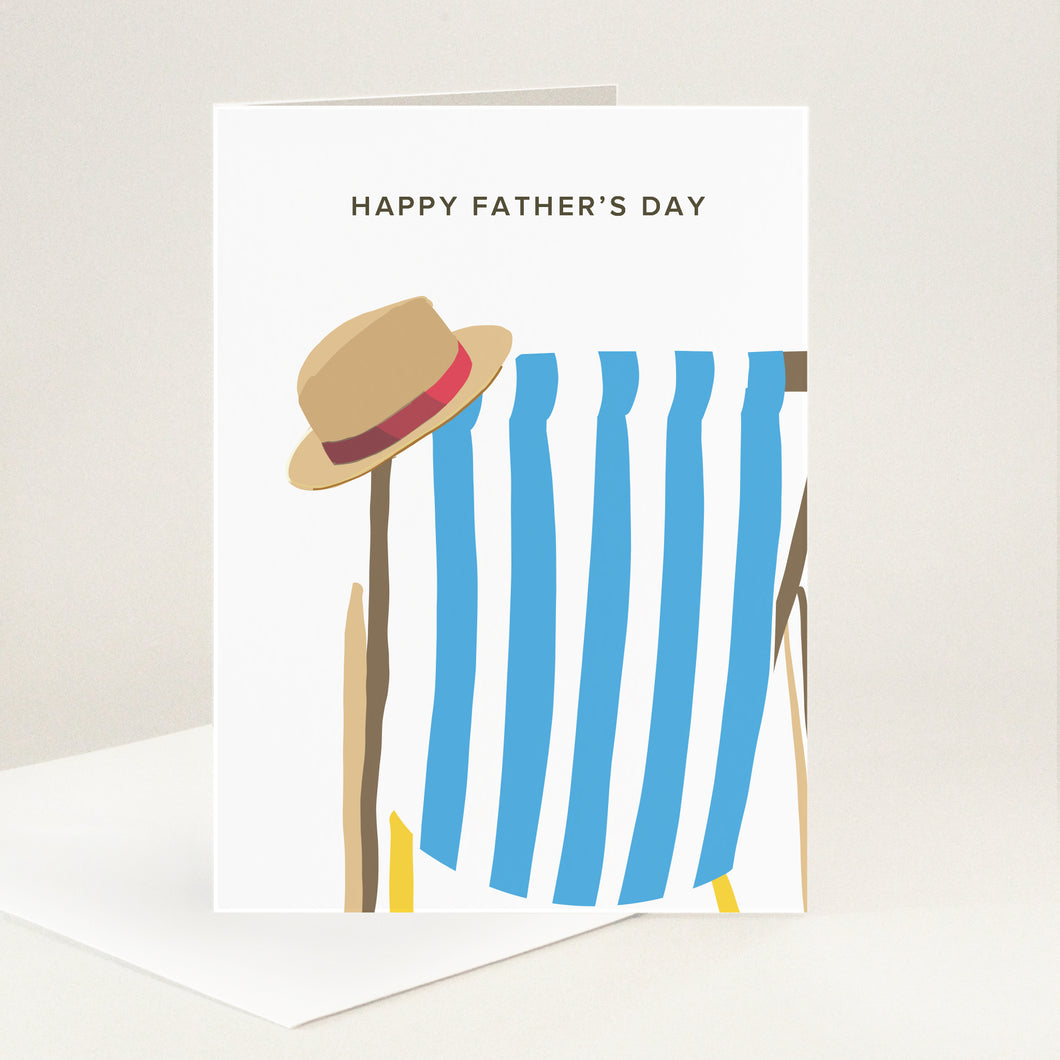 Happy Father's Day message above a blue and white striped deckchair with a summer hat perched on the top