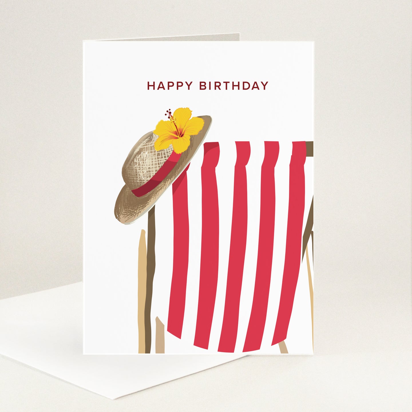 Stripy red deckchair with a wide brimmed straw sunhat and hibiscus flower balanced on the side.