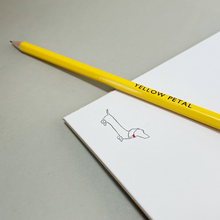 Load image into Gallery viewer, Inside page of notebook showing an illustration of a sausage dog with a red collar and a yellow pencil.
